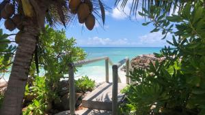 una escalera a la playa con el océano en el fondo en Sunset Cove Villa, en Grand'Anse Praslin