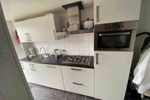 een keuken met witte kasten en een kookplaat oven bij Schrijvershuisje - sfeer & stilte Zeeuws Vlaanderen in Zaamslag +4 foto's