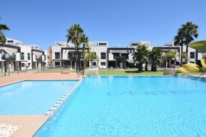 een groot zwembad met gebouwen op de achtergrond bij Oasis Beach in Orihuela