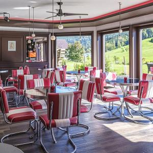 a restaurant with red chairs and tables and windows at Das Thiers in Thiersee