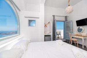 um quarto branco com uma cama grande e uma secretária em Katris Apartments em Fira