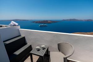 a balcony with a table and a chair and water at Katris Apartments in Fira