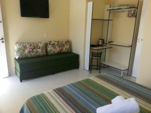 ein Wohnzimmer mit einem grünen Sofa und einem Tisch in der Unterkunft Pousada Porto Paraiso, o seu Paraíso Escondido no Guarujá in Guarujá