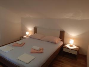a bedroom with a large bed with two lamps on it at Apartments Nikola Caska in Novalja