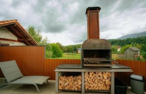 een grill met een stapel brandhout naast een stoel bij Casa DAVIDEN in Moisei