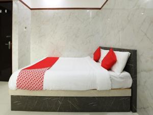 a bedroom with a bed with red and white pillows at Guru Comforts Belur in Belūr