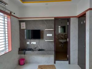 a bathroom with a sink and a television on a wall at Guru Comforts Belur in Belūr