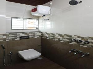a bathroom with a toilet and a sink and a window at Guru Comforts Belur in Belūr