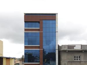 a tall glass building with a lot of windows at Guru Comforts Belur in Belūr