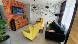 a living room with a couch and two yellow chairs at Apartament Garncarska in Elblag