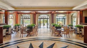 a dining room with tables and chairs and windows at Hyatt Regency Thessaloniki in Thessaloniki