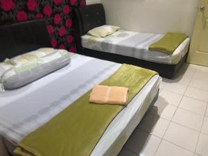2 Betten in einem Zimmer mit grüner Bettwäsche in der Unterkunft No 96 Nazirin Homestay Lumut in Lumut