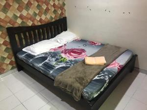 a bed with a black frame with flowers on it at No 96 Nazirin Homestay Lumut in Lumut