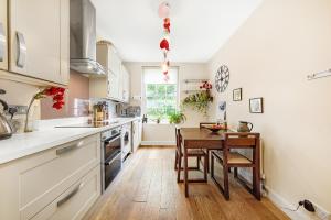 a kitchen with white cabinets and a wooden table at Veeve - Cosy in the Heart of Angel in London