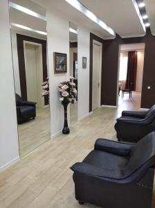 una sala de espera con sillas negras y un jarrón de flores en Tskaltubo Apartment Mirian Mepe en Tskaltubo