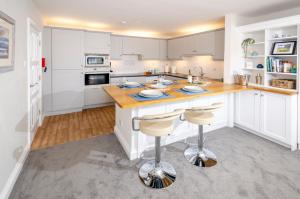 a kitchen with white cabinets and a island with bar stools at Fell View Retreat in Ambleside