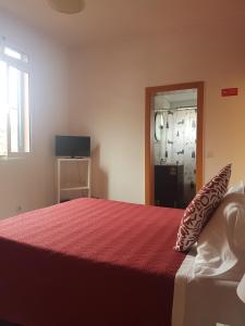 a bedroom with a bed with a red blanket and a window at FX Carvalhal in Funchal