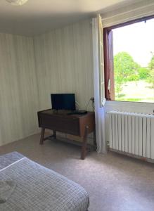 a bedroom with a desk with a computer and a window at Appartement La Libellule, professionnels et vacanciers in Compreignac