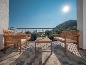 eine Terrasse mit 3 Bänken und einem Tisch auf dem Balkon in der Unterkunft Villa Tranquila in Budva