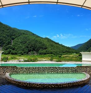una piscina d'acqua con montagne sullo sfondo di Pine Forest Jeongseon Alpine Resort a Jeongseon