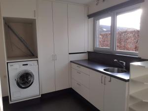 cocina blanca con fregadero y lavadora en Hoevetoerisme Op 't Zand, en Neerpelt