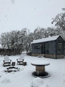 ein schneebedeckter Park mit einem Tisch und Bänken in der Unterkunft Big Yard Escapes - Two Off-Grid Tiny Houses on the Mowamba River in Jindabyne