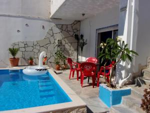 une terrasse avec une piscine, des chaises rouges et une table dans l'établissement Galini, à Kato Zakros