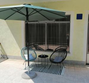 Apartman Hana في Lički Osik: كرسيين وطاولة تحت مظلة