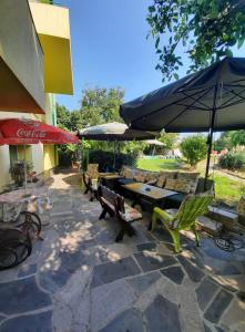 a patio with benches and tables and umbrellas at Jacky's House in Chernomorets