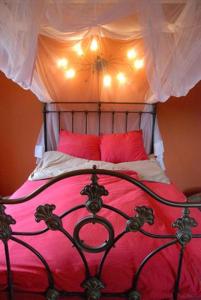 a bed with pink sheets and red pillows at Waard van Kekerdom in Kekerdom +33 photos