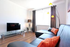 a living room with a couch and a tv at Town and Country Birchlee Road Apartments in Inverurie