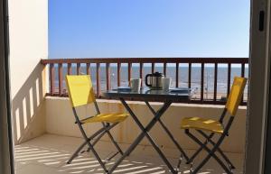 2 chaises jaunes et une table sur un balcon dans l'établissement Studio Front de Mer, à Saint-Jean-de-Monts