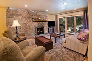 a living room with a stone wall with a fireplace at Beaver Creek West 14 in Avon