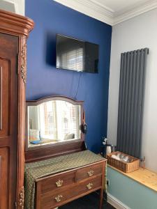 a bedroom with a mirror and a tv on the wall at Greyfriars Guest House in Bridlington