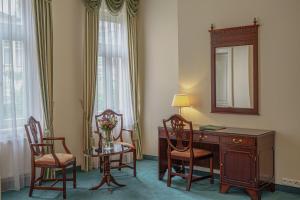 カルロヴィ・ヴァリにあるHotel Mignonのデスク、椅子、鏡が備わる客室です。