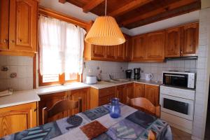 cocina con armarios de madera, mesa y lámpara en Sonia's Apartment in Fiscardo Waterfront, en Fiskardho