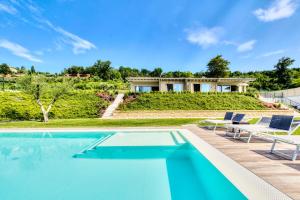 a swimming pool with chairs and a house at Villa Brusadela Suites Garda in Garda