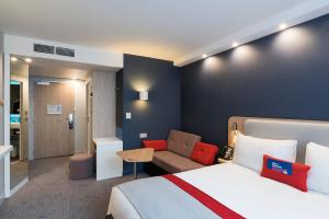 um quarto de hotel com uma cama e um sofá em Holiday Inn Express - Paris - CDG Airport, an IHG Hotel em Roissy