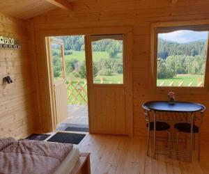 Zimmer mit einem Tisch und einem Fenster in einer Hütte in der Unterkunft Little Lucky Hope Ranch in Innernzell