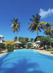 a large swimming pool with palm trees in the background at Flame Tree Cottages in Nungwi