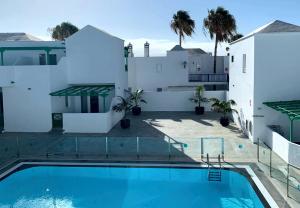 a swimming pool in front of a white house at Apartamentos Celeste in Costa Teguise