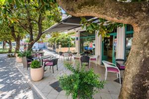 ein Café im Freien mit Tischen, Stühlen und Bäumen in der Unterkunft Hotel MB in Metković
