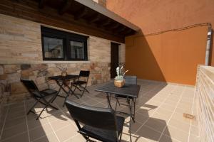 eine Terrasse mit zwei Tischen und Stühlen neben einer Wand in der Unterkunft Hotel Rural La Casa de Mis Abuelos in Navaleno