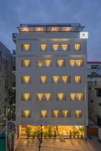 a tall white building with windows at dusk at SKYLA Studios & Suites - Hitech City in Hyderabad