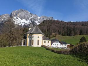a house on a hill with mountains in the background at Ferienwohnung Haus Aschauer in Oberau