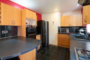 a kitchen with wooden cabinets and a black refrigerator at 4br-7guests-freeparking-garden-wifi in Derby +26 photos