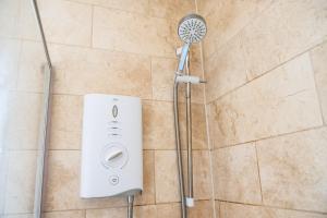 a shower with a shower head on a wall at 4br-7guests-freeparking-garden-wifi in Derby