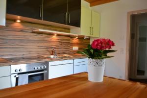 a kitchen with a vase of flowers on a table at Ferienwohnung Haus Aschauer in Oberau +16 photos