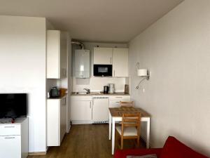 een kleine keuken met witte kasten en een kleine tafel bij Haus Atlantic Whg. 402 in Cuxhaven