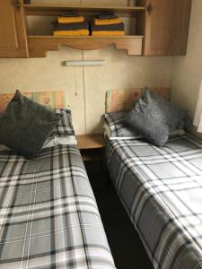 two beds in a small room with at Curacao Caravans in Taynuilt